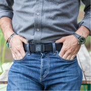 Man wearing Jelt Venture belt in black leans against a picnic table.